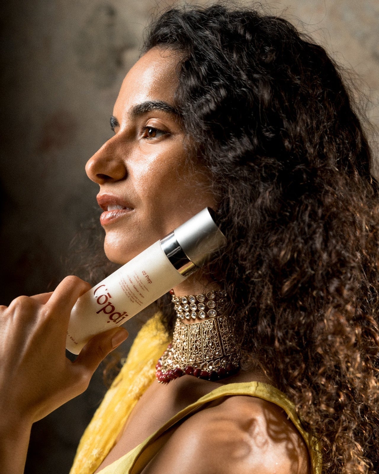 Woman holding a Cōpdī skincare bottle, considering whether peptides are safe during pregnancy.
