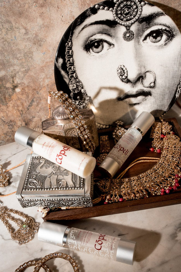 Cōpḍī Prep and Plump bottles with gold jewellery and a decorative plate
