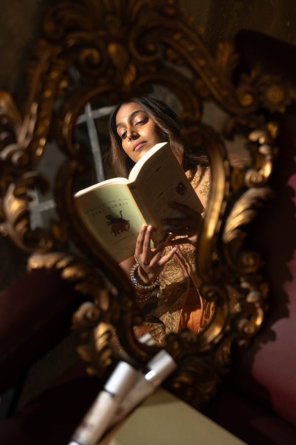 woman's reflection in a mirror reading about her hormonal skin